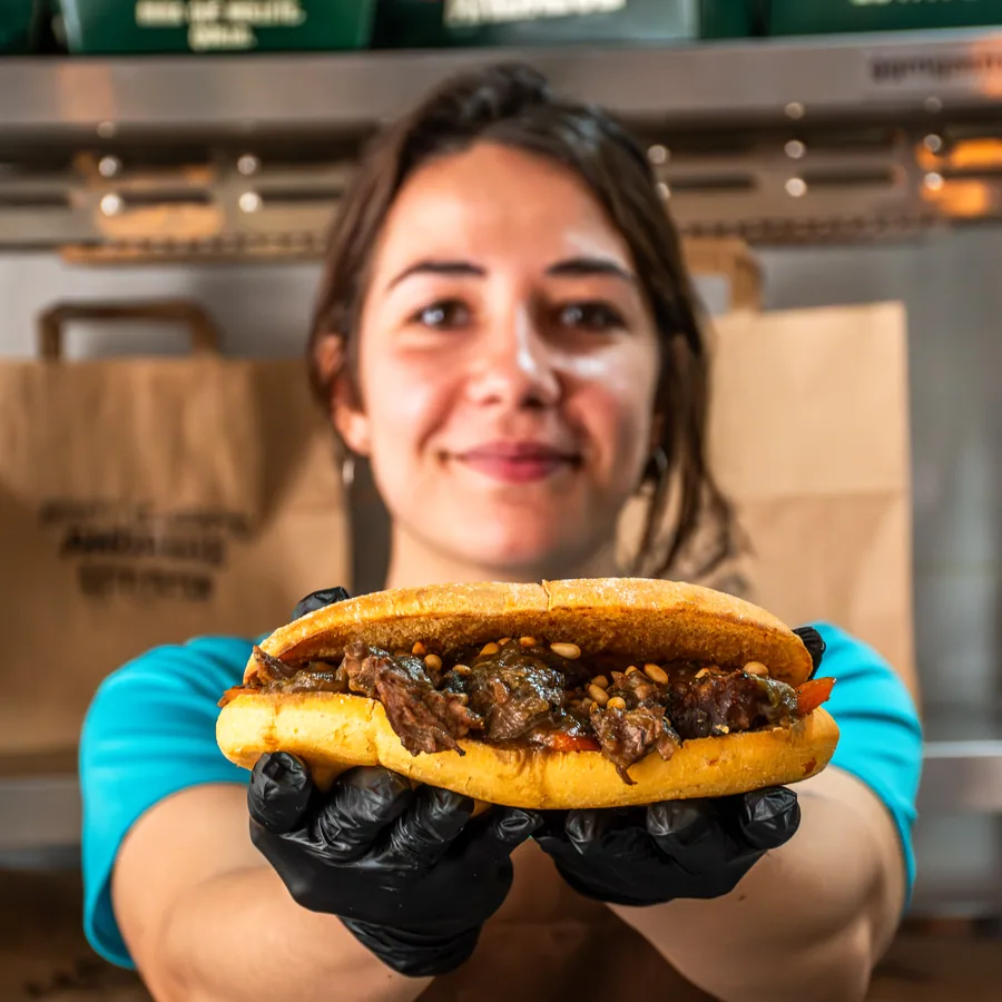 Miembro del equipo de Está Fetén mostrando un mollete de carne mechada recién montado