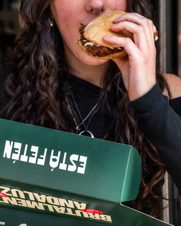 Clienta comiendo un mollete junto a la caja verde de Está Fetén