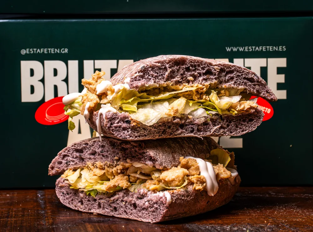 Mollete vegano frente a las cajas de Está Fetén impresas con la marca
